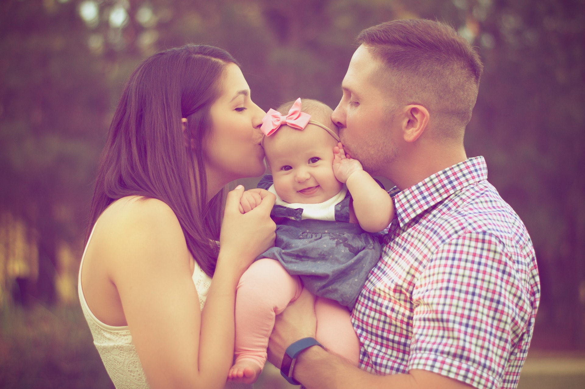 Father and mother kissing baby