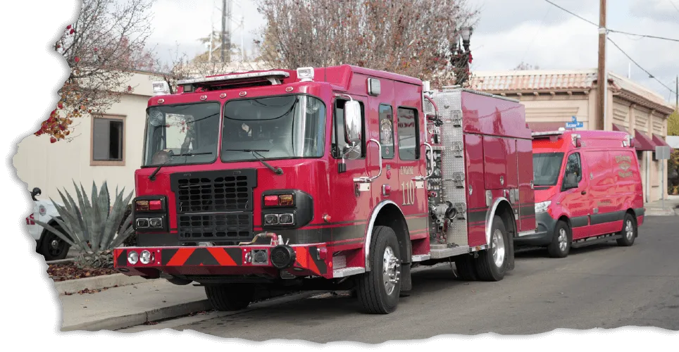 Red fire engine from Engine 110 parked on a city street with another emergency vehicle behind it.